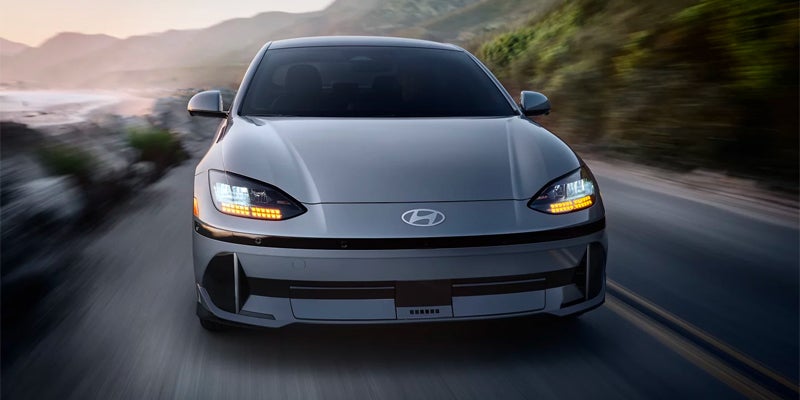 Front view of silver electric sedan driving on a road in motion
