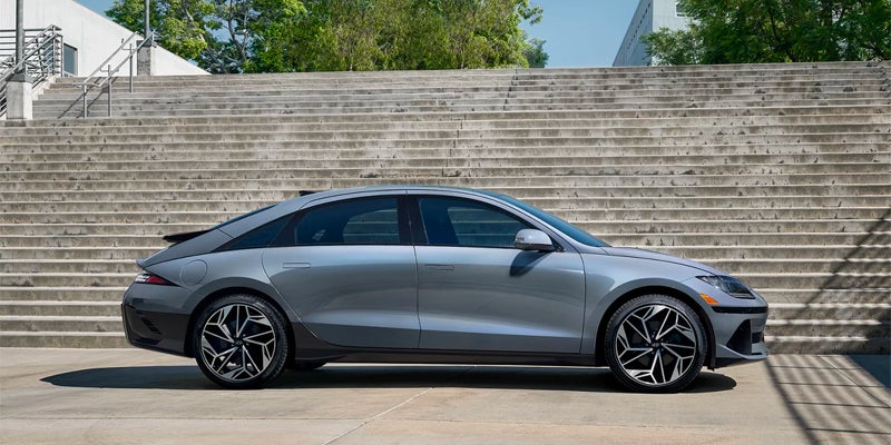 Side profile of sleek silver electric sedan parked near modern steps