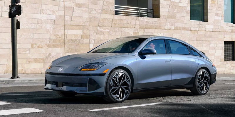 Front angle view of silver electric sedan parked outside modern building