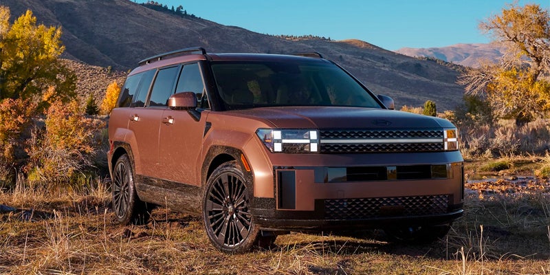 Front view of copper SUV parked outdoors in a scenic autumn landscape