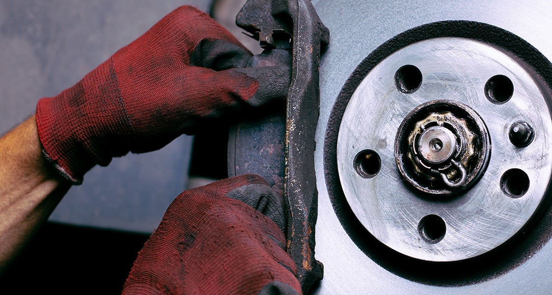 Gloved hands working to replace brake pads and rotors on a vehicle